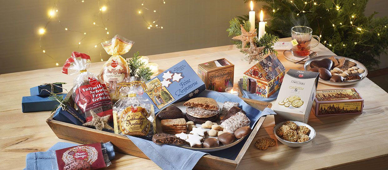 Inhalt des Begrüßungs-Päckchen mit weihnachtlicher Szene und Weihnachtsbaum im Hintergrund