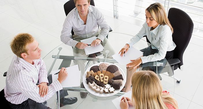 4 Personen beim Meeting mit Lebkuchen auf dem Tisch