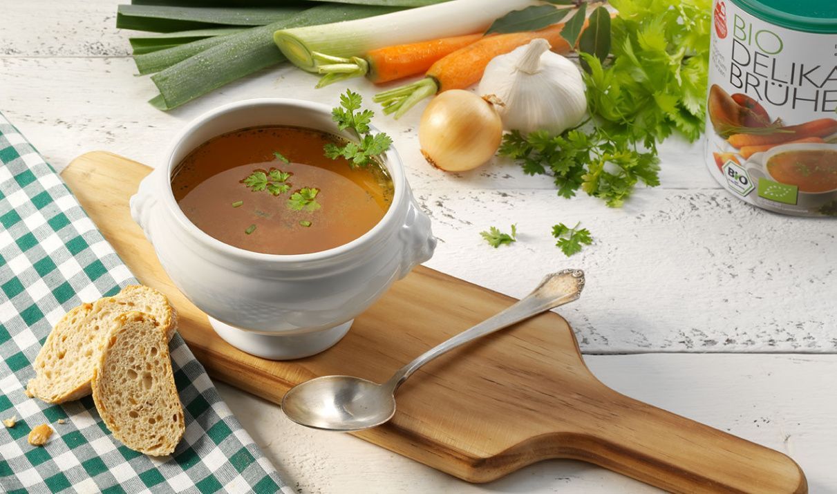 Suppe mit Brot auf einem weißen Holztisch